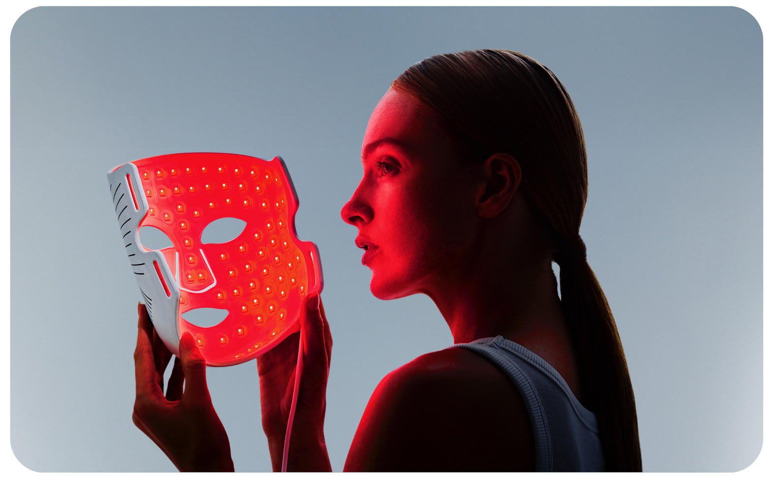 Woman using glowing red LED face mask - CurrentBody